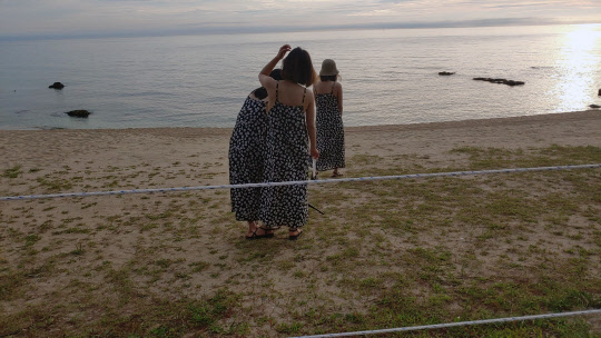 강원 강릉시가 수도권발 코로나19가 해수욕장으로 확산하는 것을 막기 위해 설치한 출입 통제선 너머에서 20일 새벽 피서객들이 기념 촬영하고 있다. 비수도권에서 처음 거리두기를 4단계로 격상한 강릉시는 오후 8시부터 다음날 오전 9까지 해수욕장 출입을 금지했다. 연합뉴스